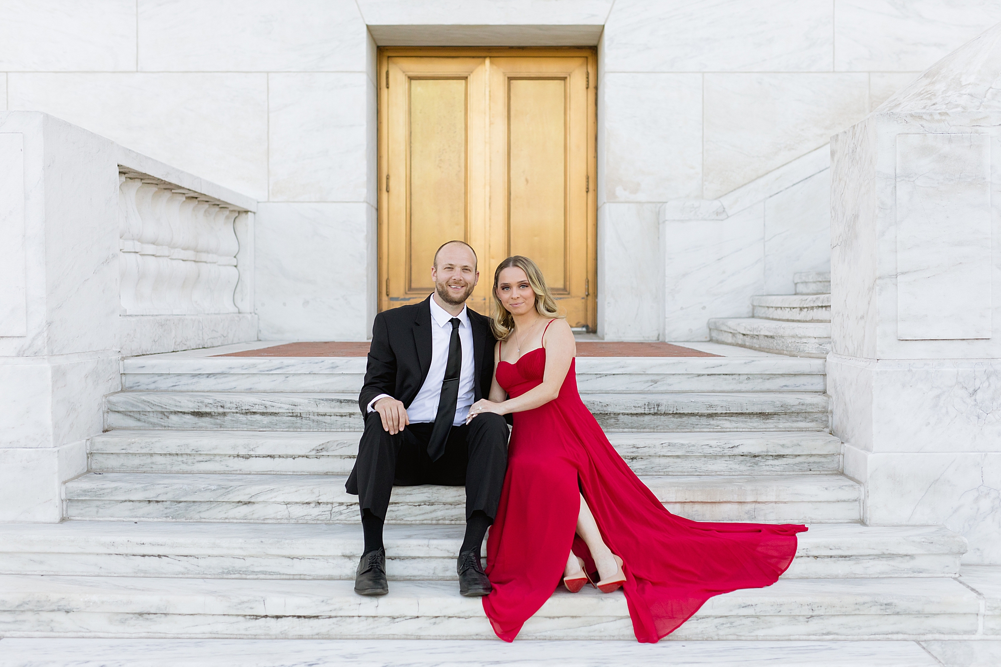Couple sitting on elegant marble staircase for engagement photos